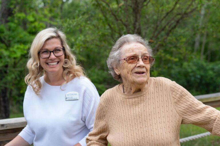 Senior living team member and resident smiling together outdoors